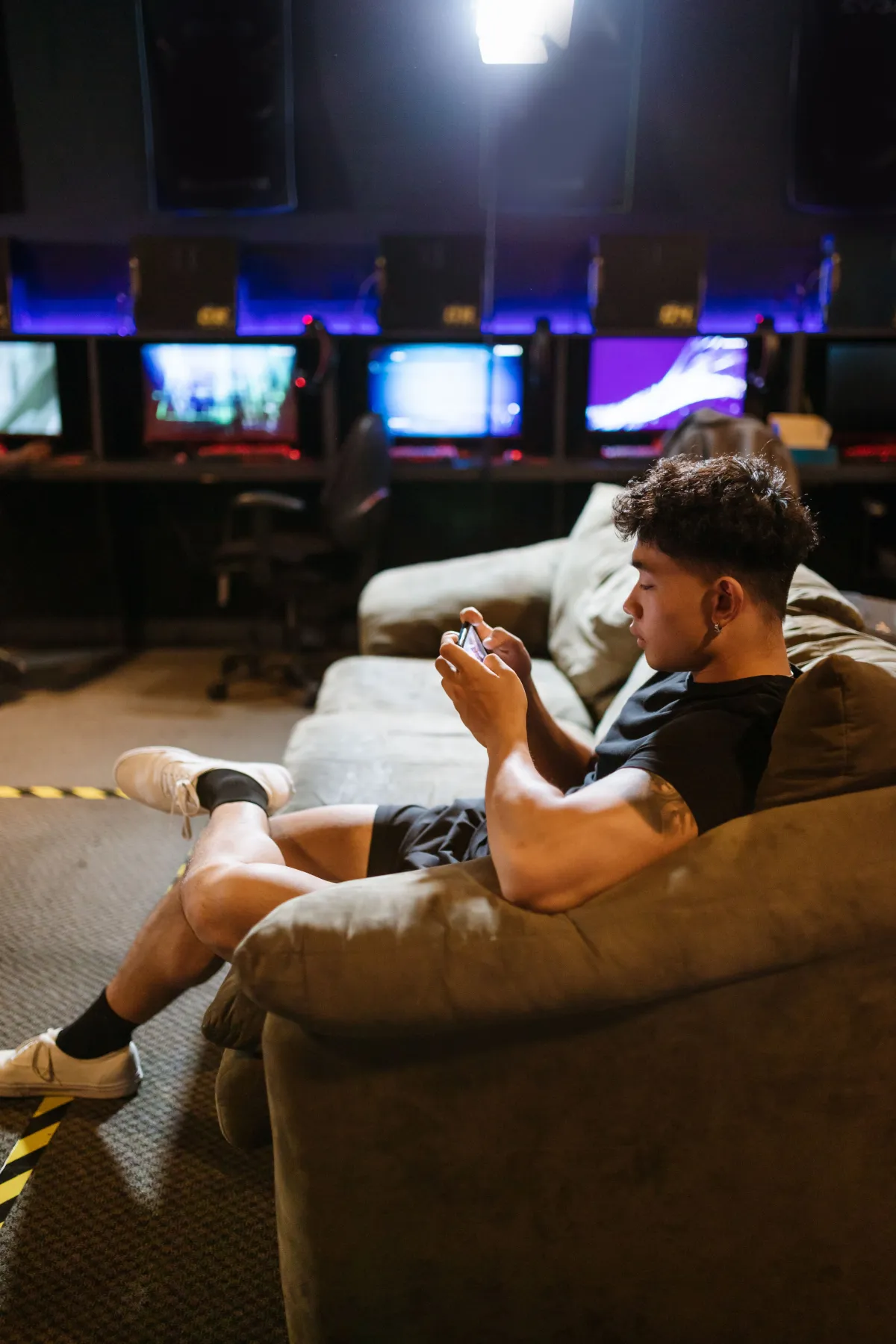 A young man on a sofa playing a mobile game in a gaming lounge
