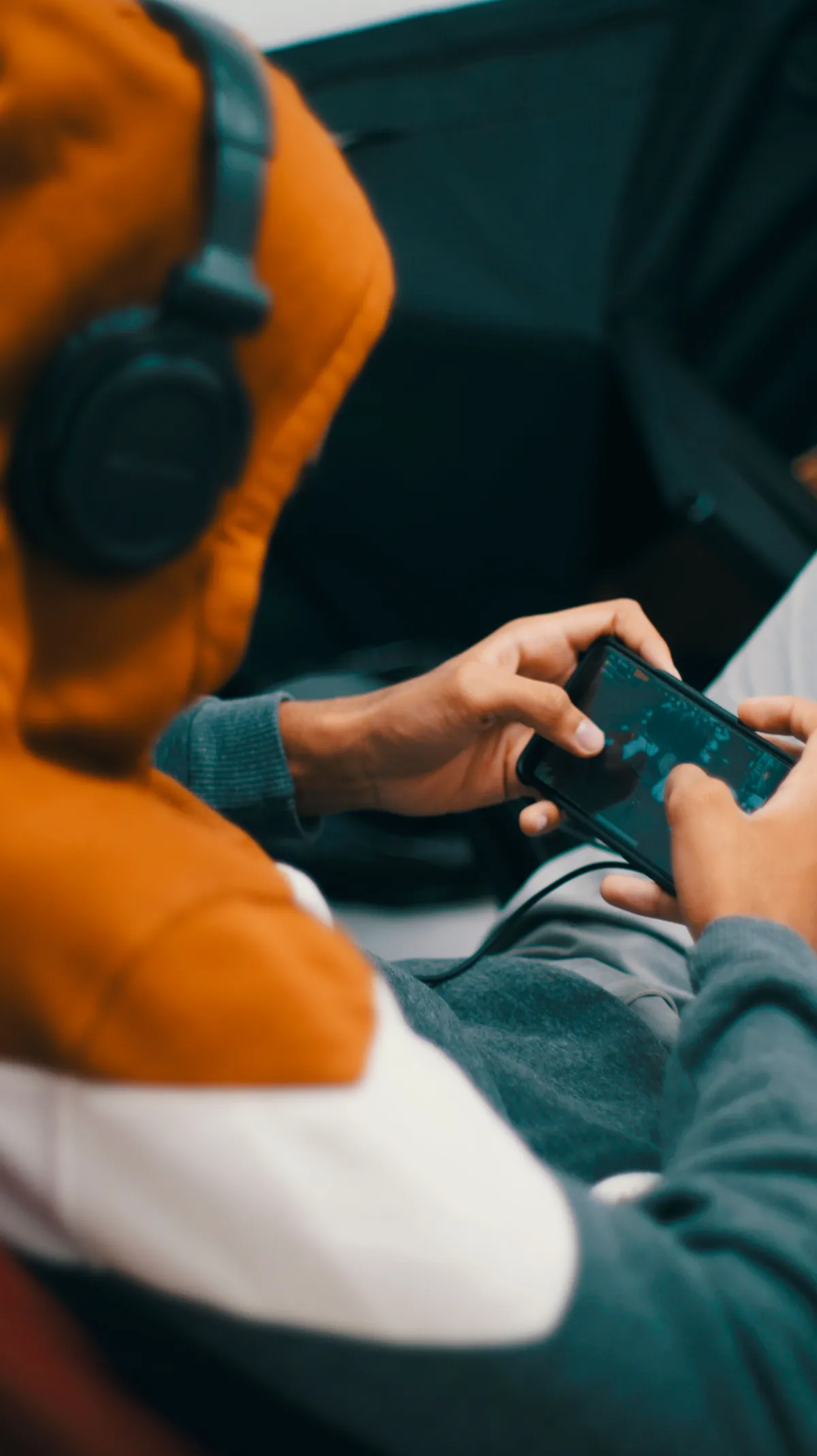 A player with headphones holding a phone during a mobile game